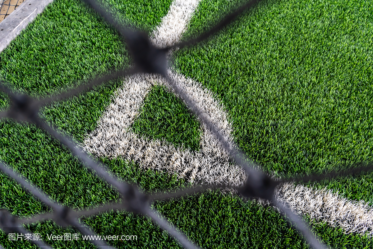 透过足球网看一个人造的绿色草地。